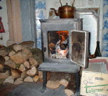 A basic woodstove with logs stacked next to it