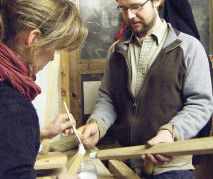 applying PVA glue to a round-tenoned stool leg with a brush before assembly; the brush ensures an even spread of glue