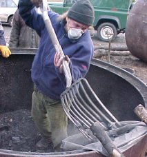 lifting the charcoal out of the kiln with a fork