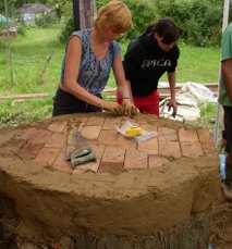 Laying fire bricks for a large earth oven with a log for a base